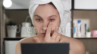 眼霜。 年轻漂亮的女人在她的左眼下面涂上奶油，女孩在浴室里照镜子